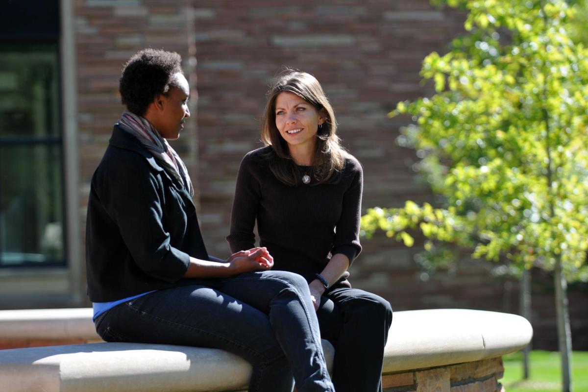 Two people meeting outside on campus for an advising session.