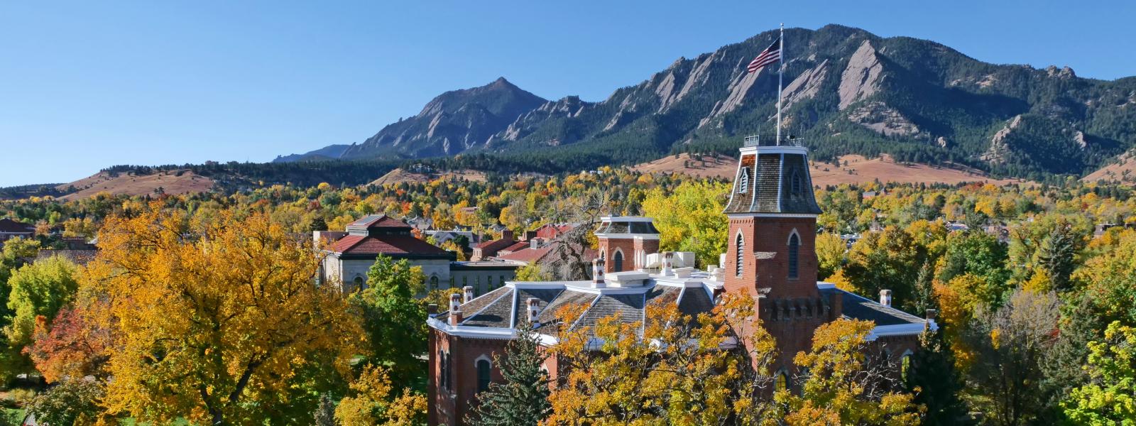 CU Boulder's Old Main during the fall, looking towards the mountains in the distance