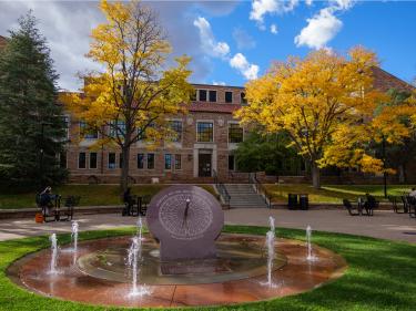 a view of the Norlin sundial and fountains with fall foliage behind